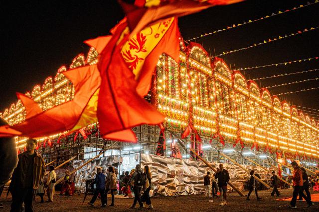 People visit a large bamboo ceremonial structure for staging rituals and performances during the decennial Jiao Festival of Kam Tin in Hong Kong on December 13, 2025. The Taoist ritual, held once every ten years, is performed to give thanks to deities, ward off misfortune and pray for peace and prosperity in the community. (Photo by Leung Man Hei / AFP)