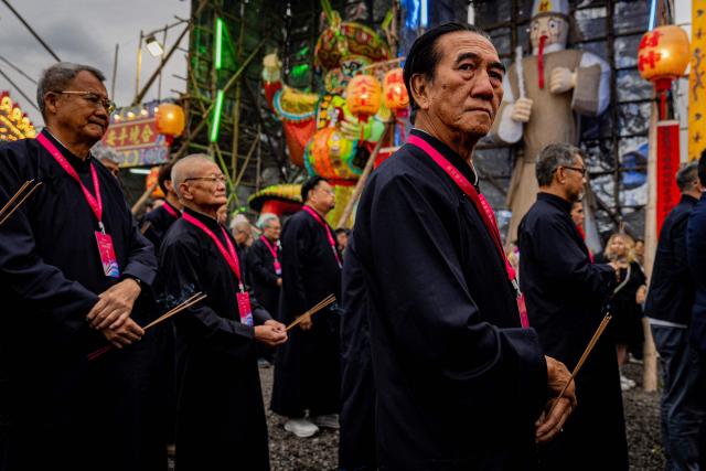 People burn incense sticks while offering prayers during the decennial Jiao Festival of Kam Tin in Hong Kong on December 13, 2025. The Taoist ritual, held once every ten years, is performed to give thanks to deities, ward off misfortune and pray for peace and prosperity in the community. (Photo by Leung Man Hei / AFP)
