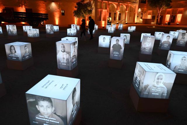 People attend an exhibition displaying portraits of 241 young victims of the war in Gaza at Msheireb Museums in Doha on December 13, 2025. The exhibition organised by Qatar Charity features 241 portraits of sponsored orphan children cared for through the compassion of donors, bringing their presence into a space where their names, faces and stories can be known and remembered. (Photo by Mahmud HAMS / AFP)