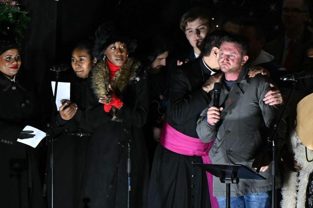 British far-right activist Tommy Robinson, whose real name is Stephen Yaxley-Lennon, reacts as he recieves a hug whist addressing supporters gathered to listen to him speak on stage, on Whitehall in central London on December 13, 2025, an outdoor carol concert event he organised. (Photo by JUSTIN TALLIS / AFP)
