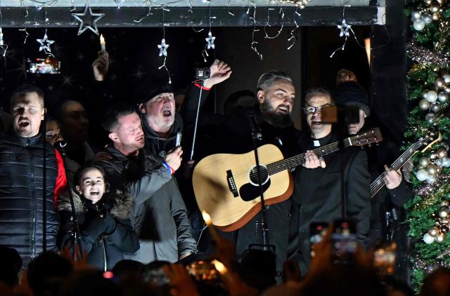 British far-right activist Tommy Robinson, whose real name is Stephen Yaxley-Lennon, uses his phone as he sings after addressing supporters gathered to listen to him speak on stage, on Whitehall in central London on December 13, 2025, an outdoor carol concert event he organised. (Photo by JUSTIN TALLIS / AFP)
