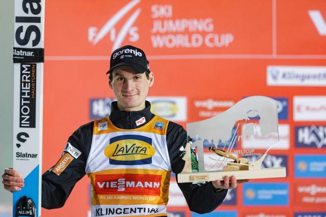 Winner Slovenia's Domen Prevc celebrates on the podium after winning the Men's Individual Large Hill HS140 event of the FIS Ski Jumping World Cup in Klingenthal, eastern Germany on December 13, 2025. Slovenia's Domen Prevc won the event ahead of Austria's Stefan Kraft (2nd) and Germany's Philipp Raimund (3rd). (Photo by JENS SCHLUETER / AFP)