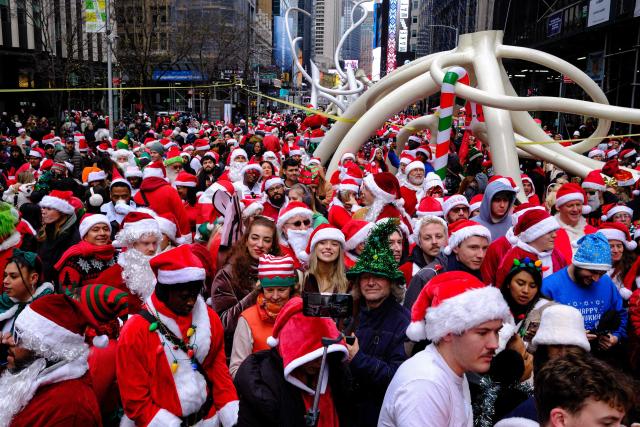 Revellers take part in the 2025 SantaCon NYC pub crawl for charity in New York on December 13, 2025. Proceeds from tickets and donations are given to various charities. (Photo by CHARLY TRIBALLEAU / AFP)