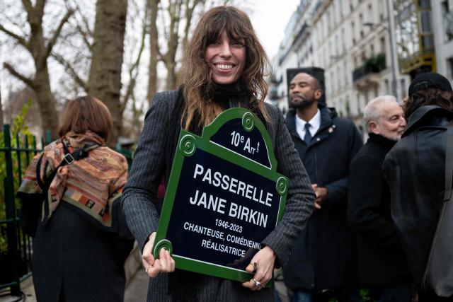 French singer and musician Lou Doillon holds a replica of a public street sign indicating the "Passerelle Jane Birkin" during a ceremony inaugurating a footbridge named after British-French actress and singer Jane Birkin, on the Quai de Valmy in Paris on December 13, 2025. (Photo by Anna KURTH / AFP)