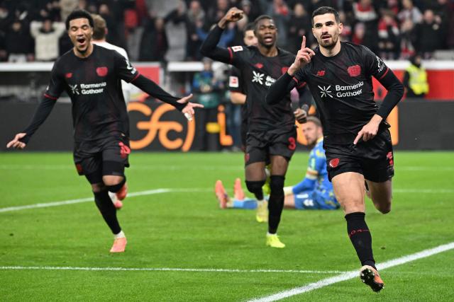 Bayer Leverkusen's French forward #11 Martin Terrier (R) celebrates scoring the opening goal with his teammates during the German first division Bundesliga football match between Bayer 04 Leverkusen and 1 FC Cologne in Leverkusen, western Germany, on December 13, 2025. (Photo by UWE KRAFT / AFP) / DFL REGULATIONS PROHIBIT ANY USE OF PHOTOGRAPHS AS IMAGE SEQUENCES AND/OR QUASI-VIDEO