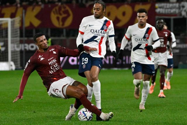 Metz's Ivorian midfielder #05 Jean-Philippe Gbamin (L) fights for the ball with Paris Saint-Germain's French forward #29 Bradley Barcola during the French L1 football match between Metz and Paris Saint-Germain (PSG) at the Stade Saint-Symphorien in Metz, eastern France, on December 13, 2025. (Photo by Jean-Christophe VERHAEGEN / AFP)