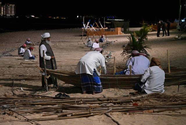 People work on a traditional hand made wooden boat in Doha on December 13, 2025. (Photo by MAHMUD HAMS / AFP)