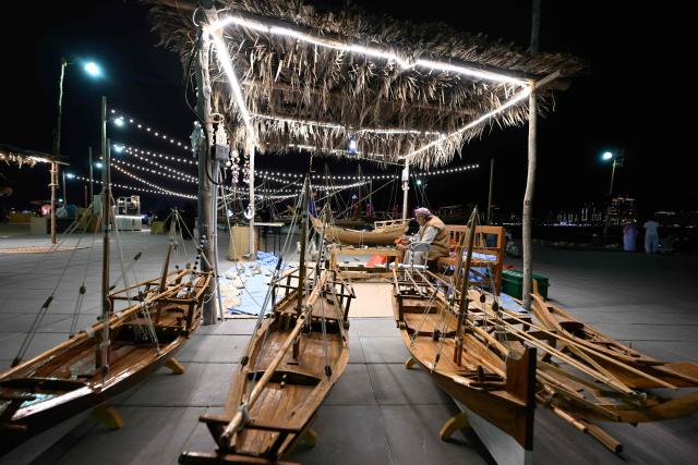 A man works on a traditional hand made wooden boat in Doha on December 13, 2025. (Photo by Mahmud HAMS / AFP)
