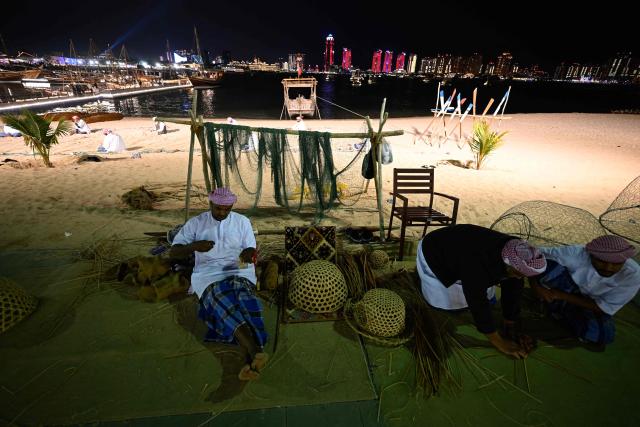 Qatari men prepare to work on traditional hand made wooden boats in Doha on December 13, 2025. (Photo by Mahmud HAMS / AFP)