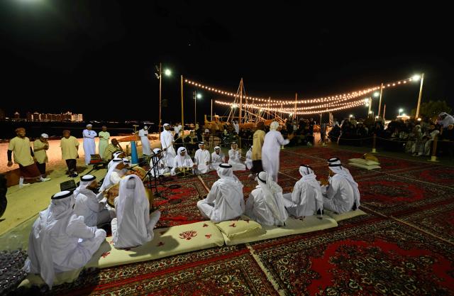 Qatari performers entertain people at a waterfront in Doha on December 13, 2025. (Photo by Mahmud HAMS / AFP)