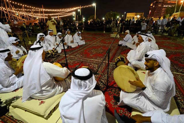Qatari performers entertain people at a waterfront during a boat show in Doha on December 13, 2025. (Photo by Mahmud HAMS / AFP)