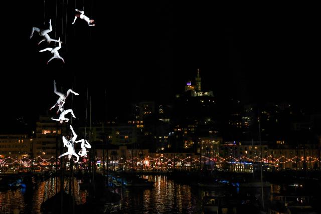 Members of the Zenit dance company perform an aerial ballet titled 'ARIA' above spectators in the old port of Marseille, southern France, during the city’s Christmas celebrations, on December 13, 2025. (Photo by Thibaud MORITZ / AFP)