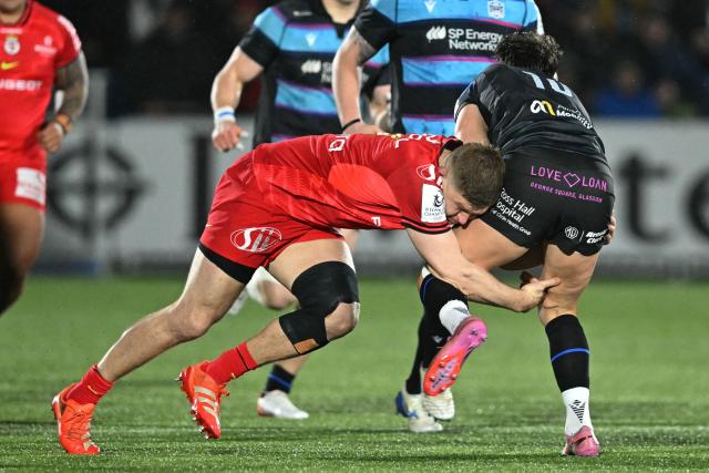 Glasgow Warriors' Scottish fly-half Adam Hastings (R) is tackled by Toulouse's English flanker Jack Willis (L) during the European Champions Cup rugby union pool 1 match between Glasgow Warriors and Toulouse at Scotstoun Stadium in Glasgow, Scotland on December 13, 2025. (Photo by ANDY BUCHANAN / AFP)