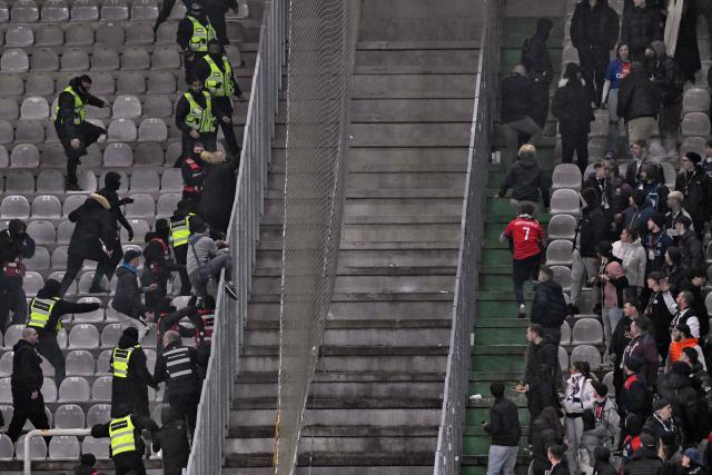 Metz's supporters (L) try to get access to the tribune of Paris' supporters at the end of the French L1 football match between Metz and Paris Saint-Germain (PSG) at the Stade Saint-Symphorien in Metz, eastern France, on December 13, 2025. (Photo by Jean-Christophe VERHAEGEN / AFP)