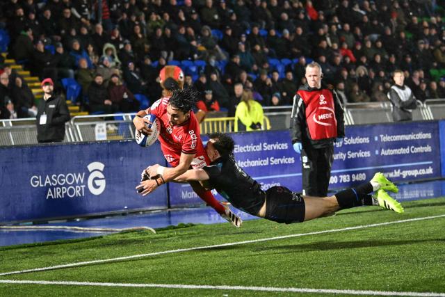 Toulouse's French wing Ange Capuozzo is tackled into touch by Glasgow Warriors' Scottish scrum-half Jamie Dobie as he reaches for the line during the European Champions Cup rugby union pool 1 match between Glasgow Warriors and Toulouse at Scotstoun Stadium in Glasgow, Scotland on December 13, 2025. (Photo by ANDY BUCHANAN / AFP)