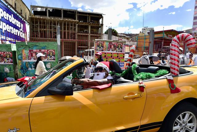 A man dressed as Santa Claus waves as he takes part in a Christmas parade in La Paz on December 13, 2025. (Photo by Jorge BERNAL / AFP)