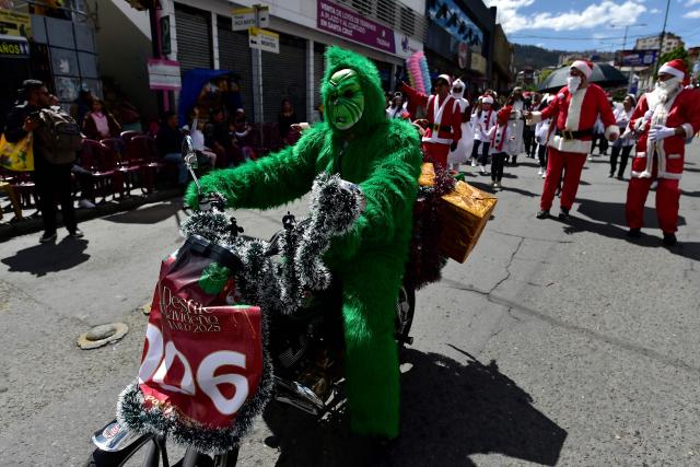 TOPSHOT - An artist dressed as the Grinch rides a motorcycle as he takes part in a Christmas parade in La Paz on December 13, 2025. (Photo by Jorge BERNAL / AFP)