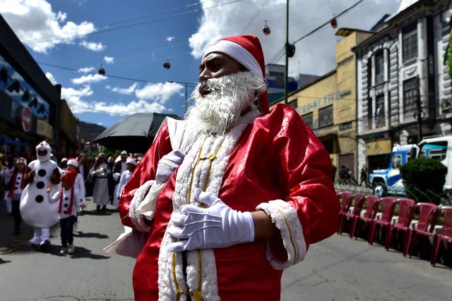A man dressed as Santa Claus waves as he takes part in a Christmas parade in La Paz on December 13, 2025. (Photo by Jorge BERNAL / AFP)