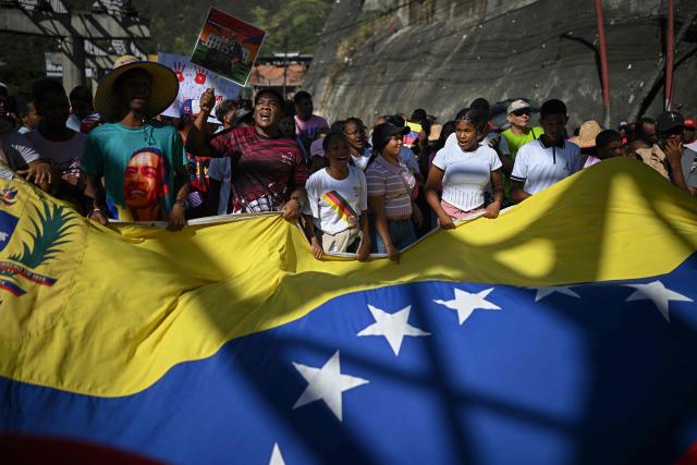 Supporters of Venezuelan President Nicolas Maduro display a giant Venezuelan flag as they take part in a rally against US military activity in the Caribbean, at the San Jose community in the Petare neighborhood in Caracas on December 13, 2025. Venezuelan President Nicolas Maduro on Thursday slammed the US seizure of an oil tanker from his country, calling it an act of "naval piracy" that escalated tensions between Washington and Caracas. (Photo by Federico PARRA / AFP)