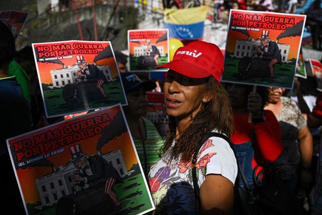 A supporter of Venezuelan President Nicolas Maduro shows a sign that reads in spanish "No more war for oil, the world demands it," as she takes part in a rally against US military activity in the Caribbean, at the San Jose community in the Petare neighborhood in Caracas on December 13, 2025. Venezuelan President Nicolas Maduro on Thursday slammed the US seizure of an oil tanker from his country, calling it an act of "naval piracy" that escalated tensions between Washington and Caracas. (Photo by Federico PARRA / AFP)