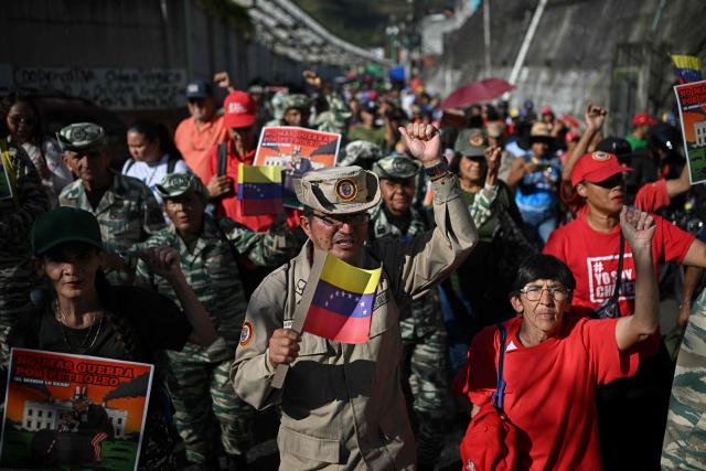 Members of the Bolivarian National Militia gesture as they take part in a rally against US military activity in the Caribbean, at the San Jose community in the Petare neighborhood in Caracas on December 13, 2025. Venezuelan President Nicolas Maduro on Thursday slammed the US seizure of an oil tanker from his country, calling it an act of "naval piracy" that escalated tensions between Washington and Caracas. (Photo by Federico PARRA / AFP)