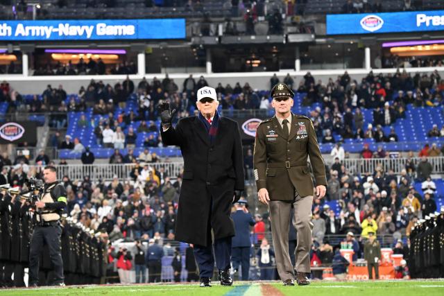 US President Donald Trump waves as he walks with Lt Gen Steven Gilland, Superintendent of the U.S. Military Academy at West Point, at the college football game between the US Army and Navy at the M&T Bank Stadium in Baltimore, Maryland, on December 13, 2025. (Photo by Alex WROBLEWSKI / AFP)