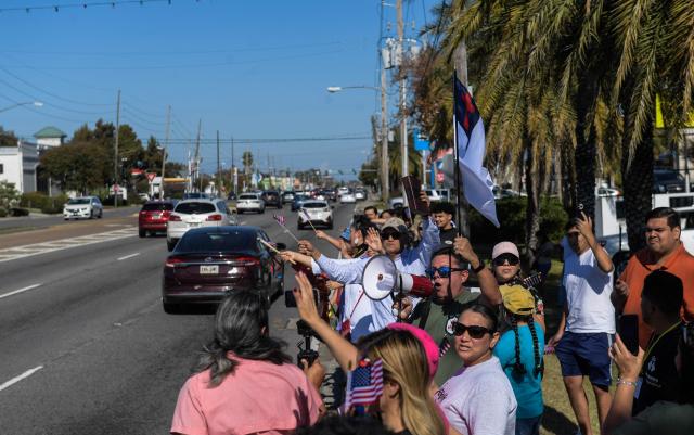 People protest against ICE and Customs and Border Protection near the parking lot of Burlington Coat Factory in Kenner, a suburb of New Orleans, Louisiana, on November 13, 2025. Customs and Border Protection agents made arrests near the Burlington Coat Factory on December 3rd and 4th after launching a federal immigration enforcement operation, named "Operation Catahoula Crunch", in the New Orleans, Louisiana area. (Photo by Matthew Hatcher / AFP)