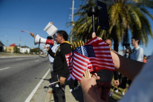 People protest against ICE and Customs and Border Protection near the parking lot of Burlington Coat Factory in Kenner, a suburb of New Orleans, Louisiana, on November 13, 2025. Customs and Border Protection agents made arrests near the Burlington Coat Factory on December 3rd and 4th after launching a federal immigration enforcement operation, named "Operation Catahoula Crunch", in the New Orleans, Louisiana area. (Photo by Matthew Hatcher / AFP)
