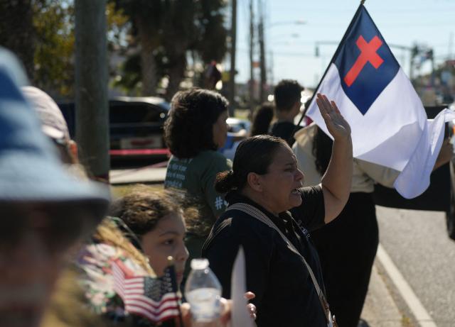People protest against ICE and Customs and Border Protection near the parking lot of Burlington Coat Factory in Kenner, a suburb of New Orleans, Louisiana, on November 13, 2025. Customs and Border Protection agents made arrests near the Burlington Coat Factory on December 3rd and 4th after launching a federal immigration enforcement operation, named "Operation Catahoula Crunch", in the New Orleans, Louisiana area. (Photo by Matthew Hatcher / AFP)