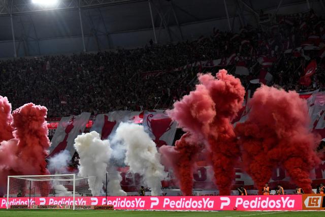 Fans of Estudiantes light smoke flares as they cheer for their team ahead of the Argentine Professional Football League 2025 Clausura Tournament final match between Racing and Estudiantes at the Madre de Ciudades stadium in Santiago del Estero, Argentina on December 13, 2025. (Photo by Luis SANTILLAN / AFP)