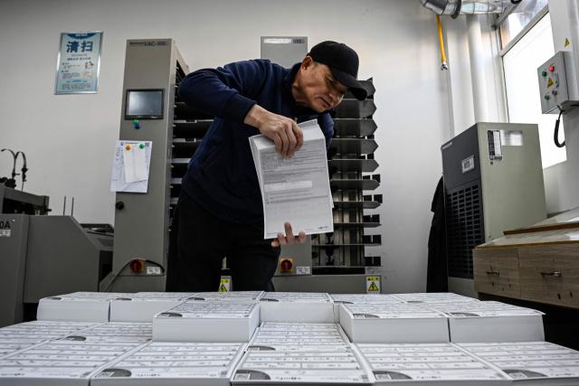 This photo taken on December 3, 2025 shows an employee working at a printing factory of Far East Precision Printing Company in Jiaxing, in eastern China's Zhejiang province. In a light-filled workshop in eastern China, a robotic arm moved a partially assembled autonomous vehicle as workers calibrated its cameras, typical of the incremental automation being adopted even across smaller factories in the world's manufacturing powerhouse. (Photo by Jade GAO / AFP) / To go with 'CHINA-ECONOMY-MANUFACTURING-TECHNOLOGY-AI, FOCUS' by Jing Xuan TENG