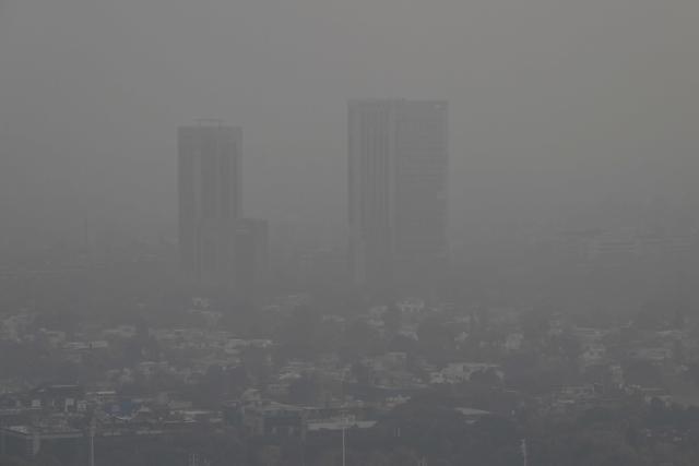 This picture taken on December 9, 2025, shows buildings engulfed in dense smog due to severe air pollution in Islamabad. Checkpoints set up this month are part of a crackdown by authorities to combat the city's soaring smog levels, with winter months the worst due to atmospheric inversions that trap pollutants at ground level. While not yet at the extreme winter levels of Lahore or the megacity Karachi, where heavy industry and brick kilns spew tons of pollutants each year, Islamabad is steadily closing the gap. (Photo by Aamir QURESHI / AFP)