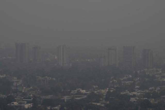 This picture taken on December 9, 2025, shows buildings engulfed in dense smog due to severe air pollution in Islamabad. Checkpoints set up this month are part of a crackdown by authorities to combat the city's soaring smog levels, with winter months the worst due to atmospheric inversions that trap pollutants at ground level. While not yet at the extreme winter levels of Lahore or the megacity Karachi, where heavy industry and brick kilns spew tons of pollutants each year, Islamabad is steadily closing the gap. (Photo by Aamir QURESHI / AFP)