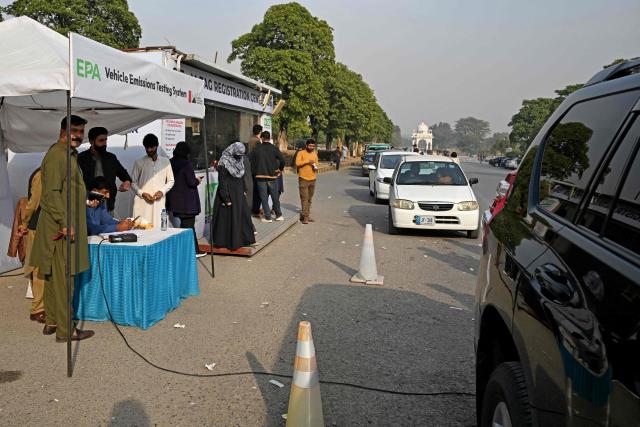 This picture taken on December 10, 2025, shows residents examining their cars at an emission testing point in Islamabad. Checkpoints set up this month are part of a crackdown by authorities to combat the city's soaring smog levels, with winter months the worst due to atmospheric inversions that trap pollutants at ground level. While not yet at the extreme winter levels of Lahore or the megacity Karachi, where heavy industry and brick kilns spew tons of pollutants each year, Islamabad is steadily closing the gap. (Photo by Aamir QURESHI / AFP)