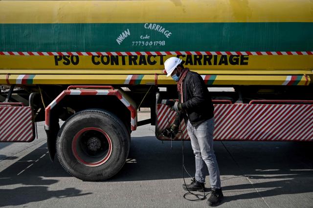 This picture taken on December 10, 2025, shows technician Waleed Ahmed examining a vehicle to test its emissions on road, on the outskirts of Islamabad. Checkpoints set up this month are part of a crackdown by authorities to combat the city's soaring smog levels, with winter months the worst due to atmospheric inversions that trap pollutants at ground level. While not yet at the extreme winter levels of Lahore or the megacity Karachi, where heavy industry and brick kilns spew tons of pollutants each year, Islamabad is steadily closing the gap. (Photo by Aamir QURESHI / AFP)