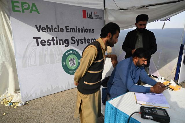 This picture taken on December 10, 2025, shows residents registering their cars at an emission testing point in Islamabad. Checkpoints set up this month are part of a crackdown by authorities to combat the city's soaring smog levels, with winter months the worst due to atmospheric inversions that trap pollutants at ground level. While not yet at the extreme winter levels of Lahore or the megacity Karachi, where heavy industry and brick kilns spew tons of pollutants each year, Islamabad is steadily closing the gap. (Photo by Aamir QURESHI / AFP)