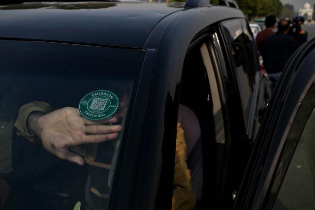 This picture taken on December 10, 2025, shows a technician pasting a certified sticker on a car after it cleared an emission test in Islamabad. Checkpoints set up this month are part of a crackdown by authorities to combat the city's soaring smog levels, with winter months the worst due to atmospheric inversions that trap pollutants at ground level. While not yet at the extreme winter levels of Lahore or the megacity Karachi, where heavy industry and brick kilns spew tons of pollutants each year, Islamabad is steadily closing the gap. (Photo by Aamir QURESHI / AFP)