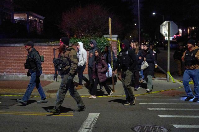 Law enforcement officers escort students near the Barus & Holley engineering building at Brown University campus in Providence, Rhode Island, on December 13, 2025. A gunman killed two people and critically wounded eight others in the afternoon of December 13 at prestigious Brown University, authorities said, urging people in the area to remain in lockdown as the attacker was still at large. (Photo by Bing Guan / AFP)