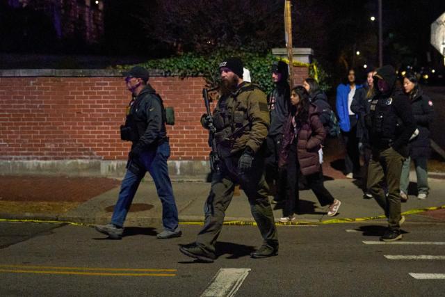 Law enforcement officers escort students near the Barus & Holley engineering building at Brown University campus in Providence, Rhode Island, on December 13, 2025. A gunman killed two people and critically wounded eight others in the afternoon of December 13 at prestigious Brown University, authorities said, urging people in the area to remain in lockdown as the attacker was still at large. (Photo by Bing Guan / AFP)