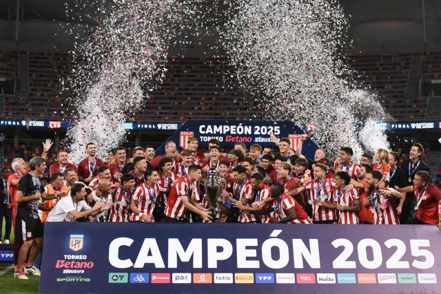 Estudiantes' midfielder #05 Santiago Ascacibar lifts the trophy next to teammates after winning the Argentine Professional Football League 2025 Clausura Tournament final match between Racing and Estudiantes at the Madre de Ciudades stadium in Santiago del Estero, Argentina on December 13, 2025. (Photo by Luis Santillan / AFP)