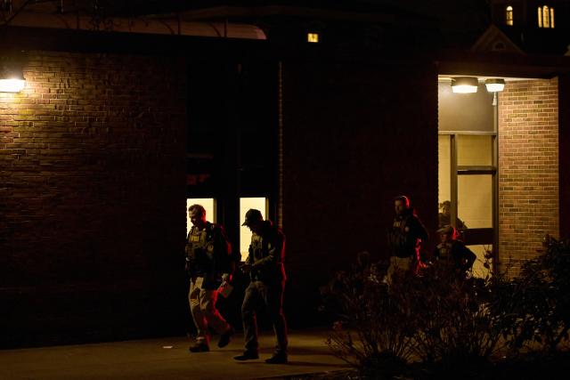 FBI agents walk toward the Barus & Holley engineering building, the site of a shooting at Brown University campus in Providence, Rhode Island, on December 13, 2025. A gunman killed two people and critically wounded eight others in the afternoon of December 13 at prestigious Brown University, authorities said, urging people in the area to remain in lockdown as the attacker was still at large. (Photo by Bing Guan / AFP)