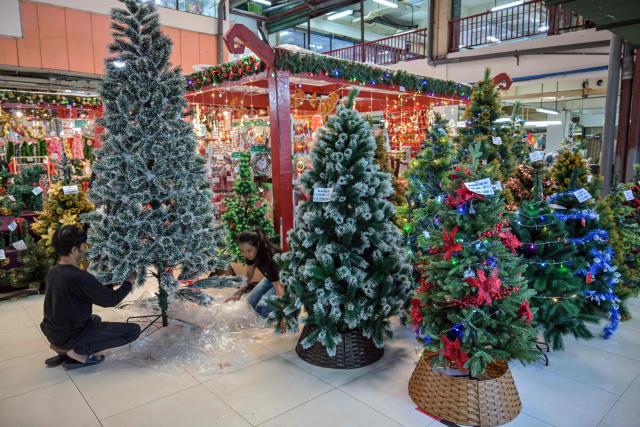 Vendors arrange Christmas decorations for sale at a mall in Surabaya on December 14, 2025. (Photo by JUNI KRISWANTO / AFP)