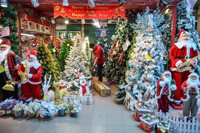 A vendor arranges Christmas decorations for sale at a mall in Surabaya on December 14, 2025. (Photo by JUNI KRISWANTO / AFP)