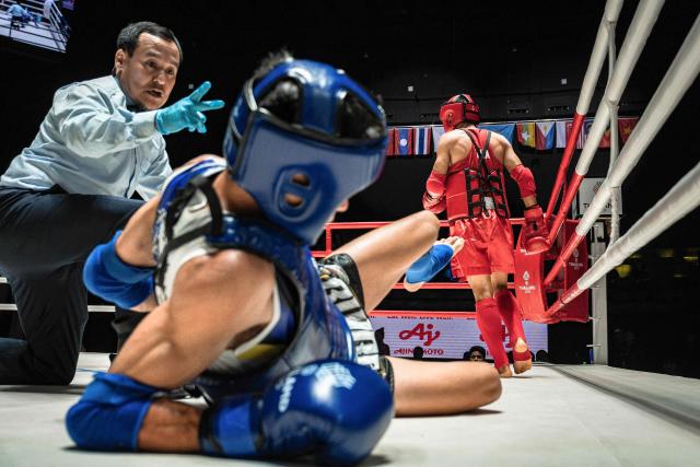CORRECTION / Vietnam’s Dang Huynh Hai (C) reacts on the ground as he competes against Thailand's Chalongchai Minindi (R) in the quarter-finals of the men's 51kg Muay Thai event of the 33rd Southeast Asian Games (SEA Games) at Lumpinee Boxing Stadium in Bangkok on December 14, 2025. (Photo by Chanakarn LAOSARAKHAM / AFP) / “The erroneous mention[s] appearing in the metadata of this photo by Chanakarn LAOSARAKHAM has been modified in AFP systems in the following manner: [the men's 51kg Muay Thai event] instead of [the women's 51kg Muay Thai event]. Please immediately remove the erroneous mention[s] from all your online services and delete it (them) from your servers. If you have been authorized by AFP to distribute it (them) to third parties, please ensure that the same actions are carried out by them. Failure to promptly comply with these instructions will entail liability on your part for any continued or post notification usage. Therefore we thank you very much for all your attention and prompt action. We are sorry for the inconvenience this notification may cause and remain at your disposal for any further information you may require.”