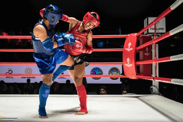Myanmar's Su Latt Nyein Chan (L) and Indonesia's Stevannie Rejune Christia (C) compete in the quarter-finals of the women's 51kg Muay Thai event of the 33rd Southeast Asian Games (SEA Games) at Lumpinee Boxing Stadium in Bangkok on December 14, 2025. (Photo by Chanakarn LAOSARAKHAM / AFP)