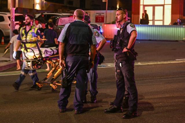 Police stand on a road after a shooting incident at Bondi Beach in Sydney on December 14, 2025. Australian police said two people were in custody following reports of multiple gunshots on December 14 at Sydney's famed Bondi Beach, urging the public to take shelter. (Photo by Saeed KHAN / AFP)