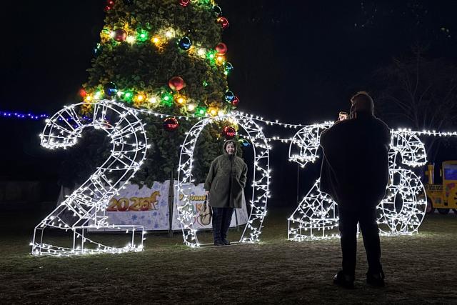 A woman poses in front of illuminated numbers for the upcoming year 2026 next to a Christmas tree in Zaporizhzhia on December 13, 2025, amid the Russian invasion of Ukraine. (Photo by Darya NAZAROVA / AFP)