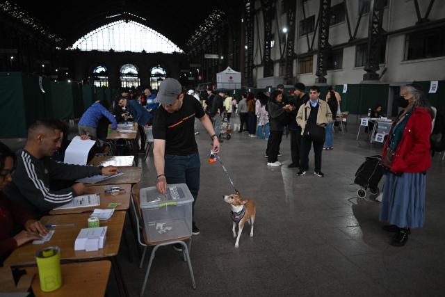 A man with a dog cast his vote during the presidential runoff election at Estacion Mapocho in Santiago on December 14, 2025. Chileans head to the polls for a presidential runoff between Jeannette Jara, a communist backed by a broad left coalition, and Jose Antonio Kast, a devout far-right politico promising a hard line on security and migration. (Photo by Eitan ABRAMOVICH / AFP)