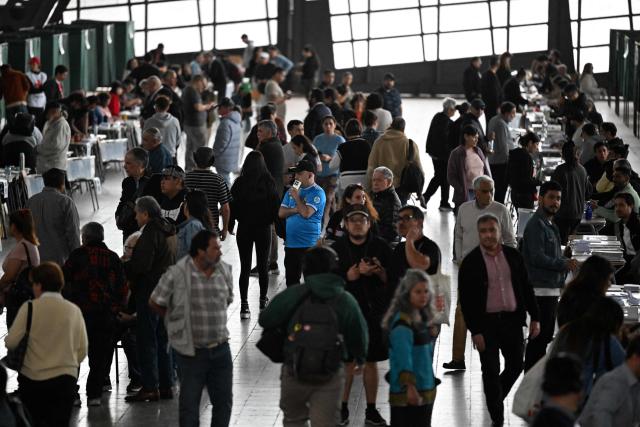 People queue to vote during the presidential runoff election at Estacion Mapocho in Santiago on December 14, 2025. Chileans head to the polls for a presidential runoff between Jeannette Jara, a communist backed by a broad left coalition, and Jose Antonio Kast, a devout far-right politico promising a hard line on security and migration. (Photo by EITAN ABRAMOVICH / AFP)