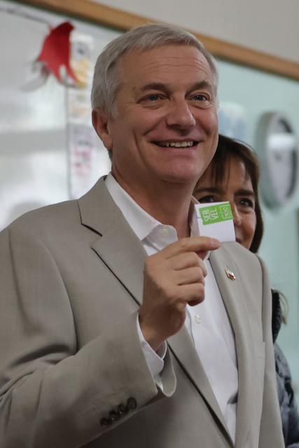 Chile's presidential candidate Jose Antonio Kast, of the Partido Republicano party, poses for a picture with his wife Maria Pia Adriasola before casting his ballot during the presidential runoff election in Paine, south of Santiago, on December 14, 2025. Chileans head to the polls for a presidential runoff between Jeannette Jara, a communist backed by a broad left coalition, and Jose Antonio Kast, a devout far-right politico promising a hard line on security and migration. (Photo by Javier TORRES / AFP)